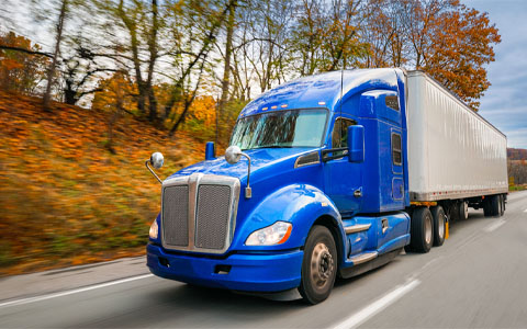 Blue 18-wheeler truck driving along highway