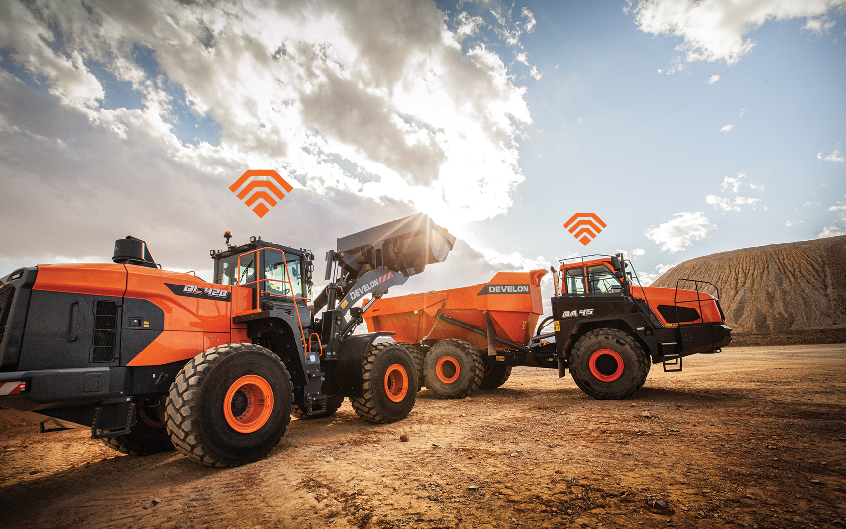 A DEVELON wheel loader and articulated dump truck using construction equipment telematics on the job site. 