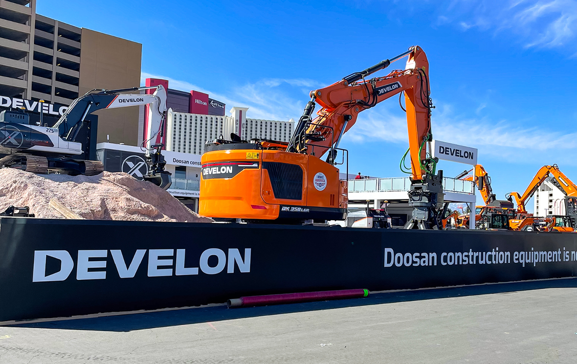 Photo at CONEXPO festival grounds looking into the demo area of the DEVELON booth featuring Concept-X2 excavator and a DEVELON DX350LCR-7 reduced tail swing crawler excavator.