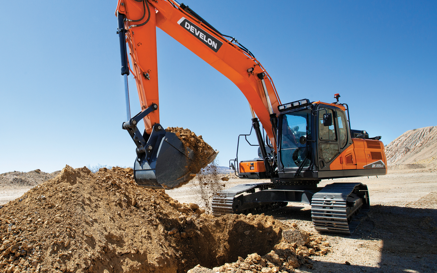 A DEVELON excavator lifts a bucket of dirt.