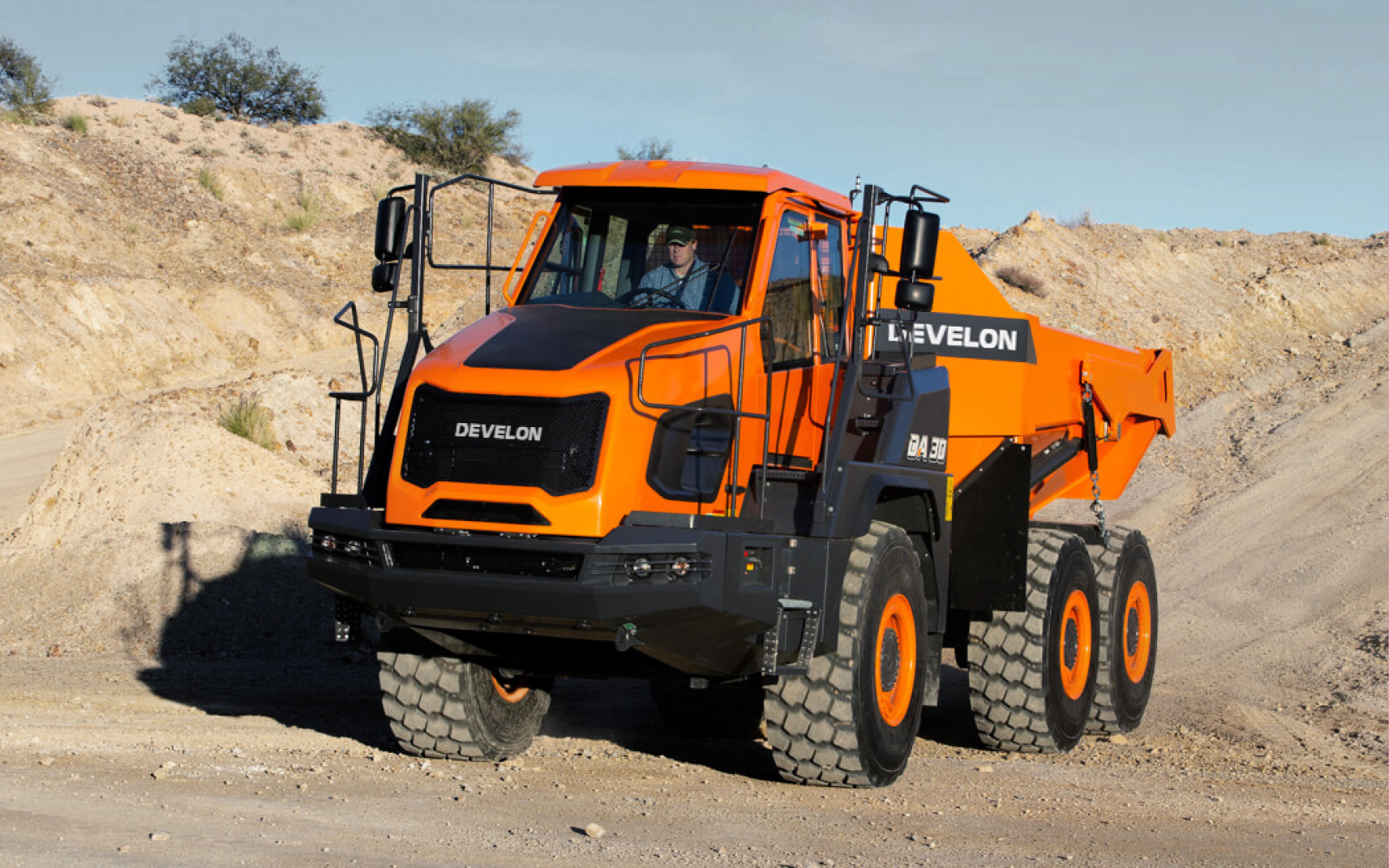 An operator in a DEVELON articulated dump truck at a job site.