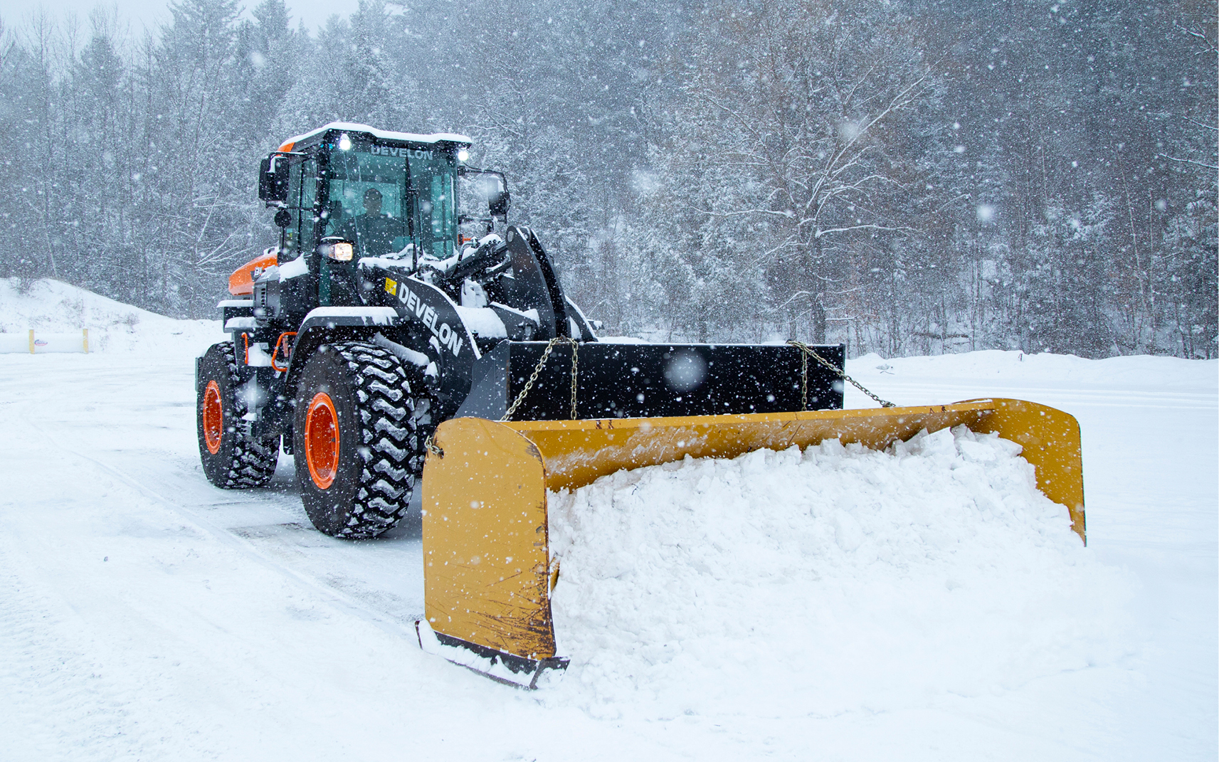 A DEVELON wheel loader pushing snow during winter.