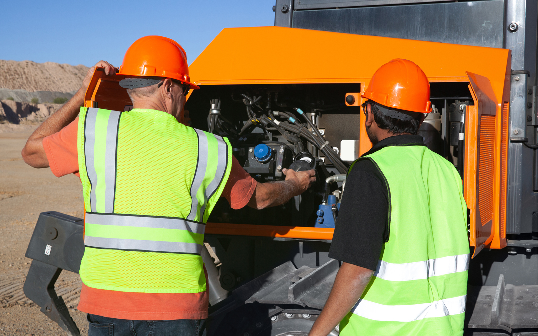 Two employees perform routine preventive maintenance on the dozer
