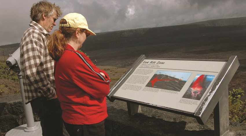 Road Scholars reading an informational sign in front of a volcanic landscape in Hawaii