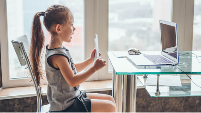 Student holding paper up to laptop webcam