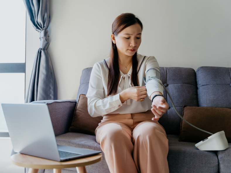 Woman on sofa checking blood pressure